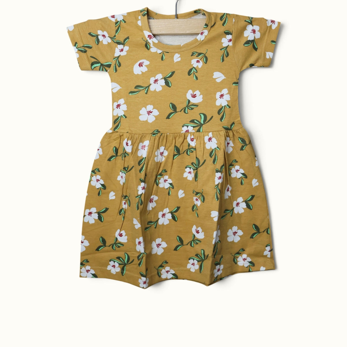 Mustard yellow baby short sleeve frock with white floral and green leaf printed design.