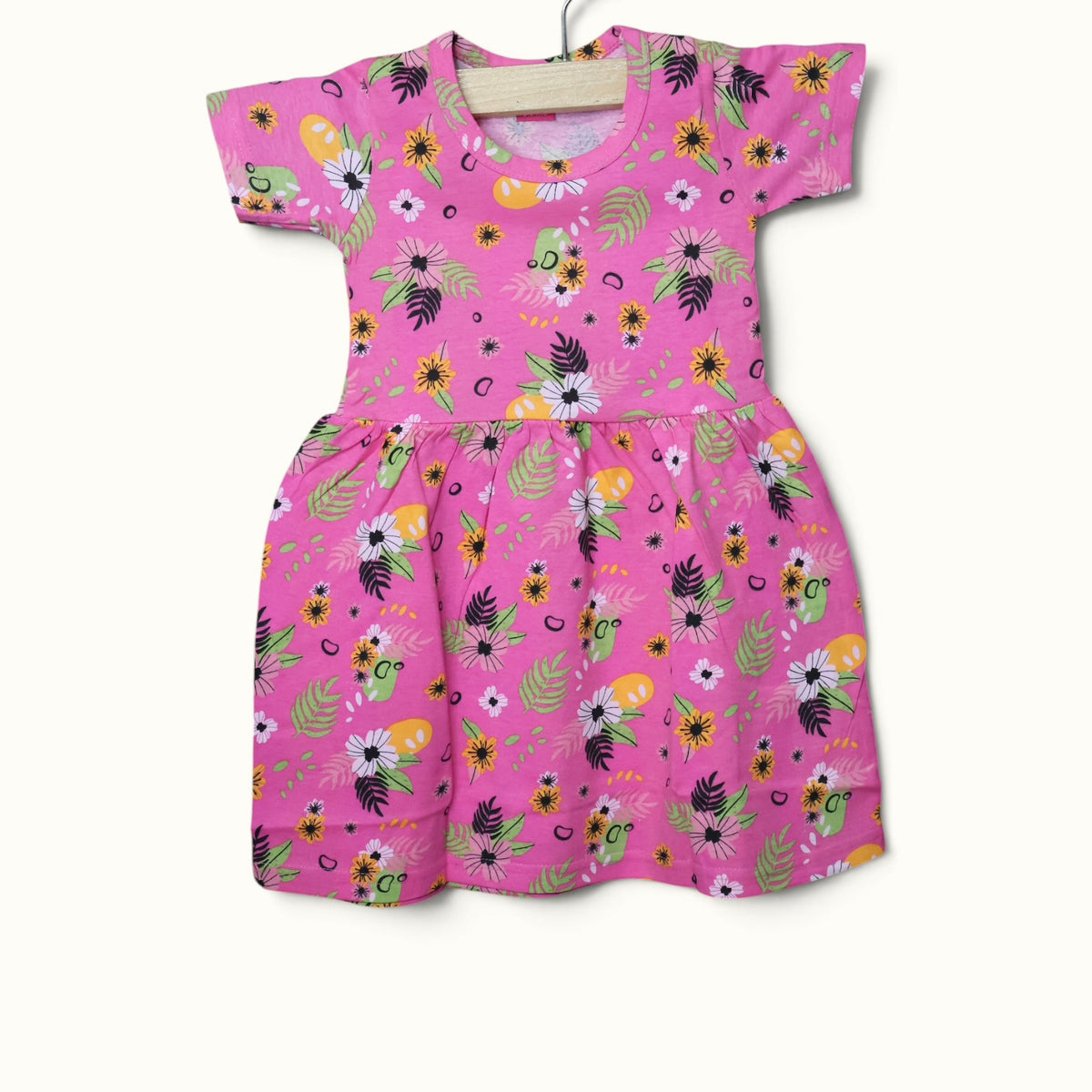 Pink baby short sleeve frock with colorful floral and leafy printed design.