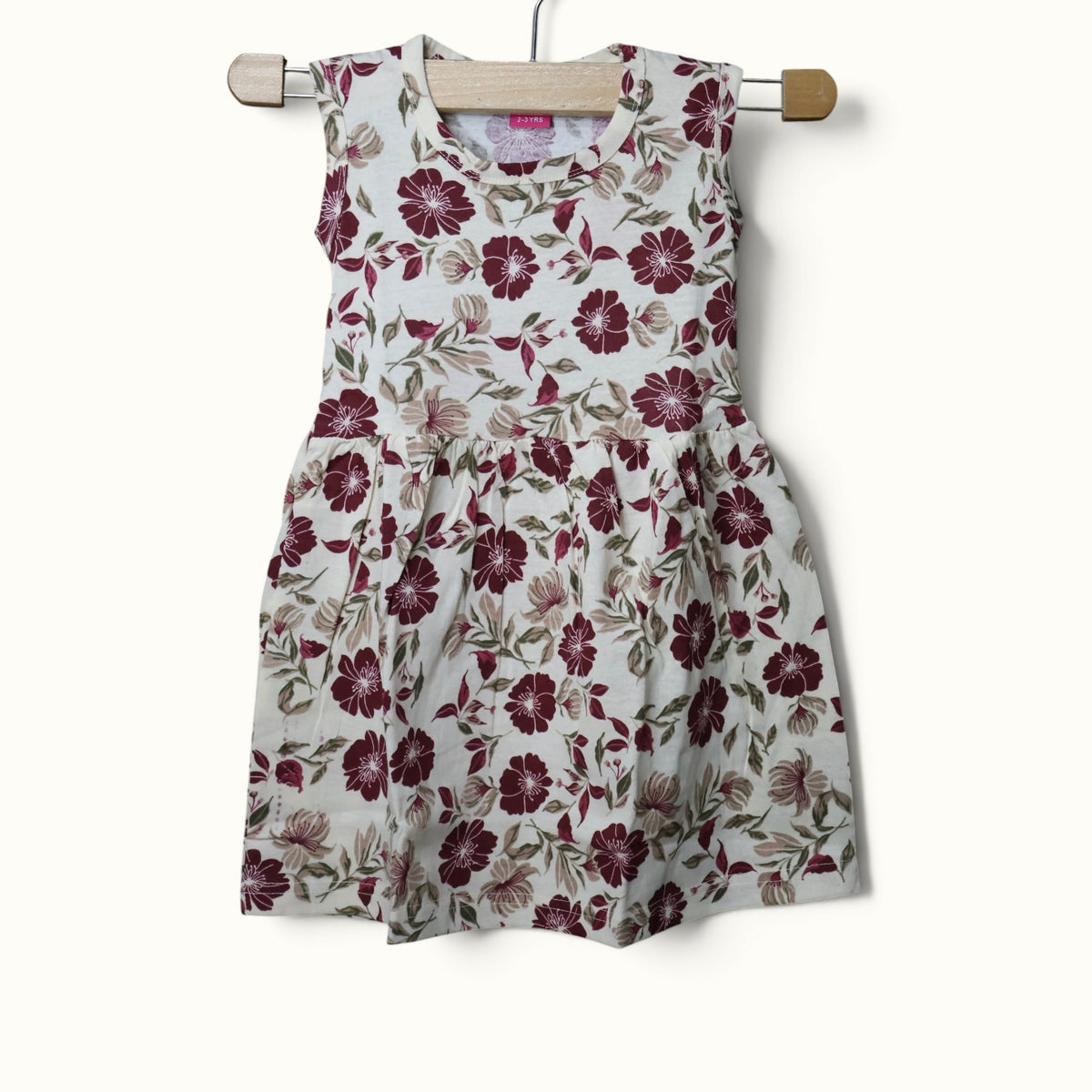 Cream baby sleeveless frock with maroon and green floral printed design