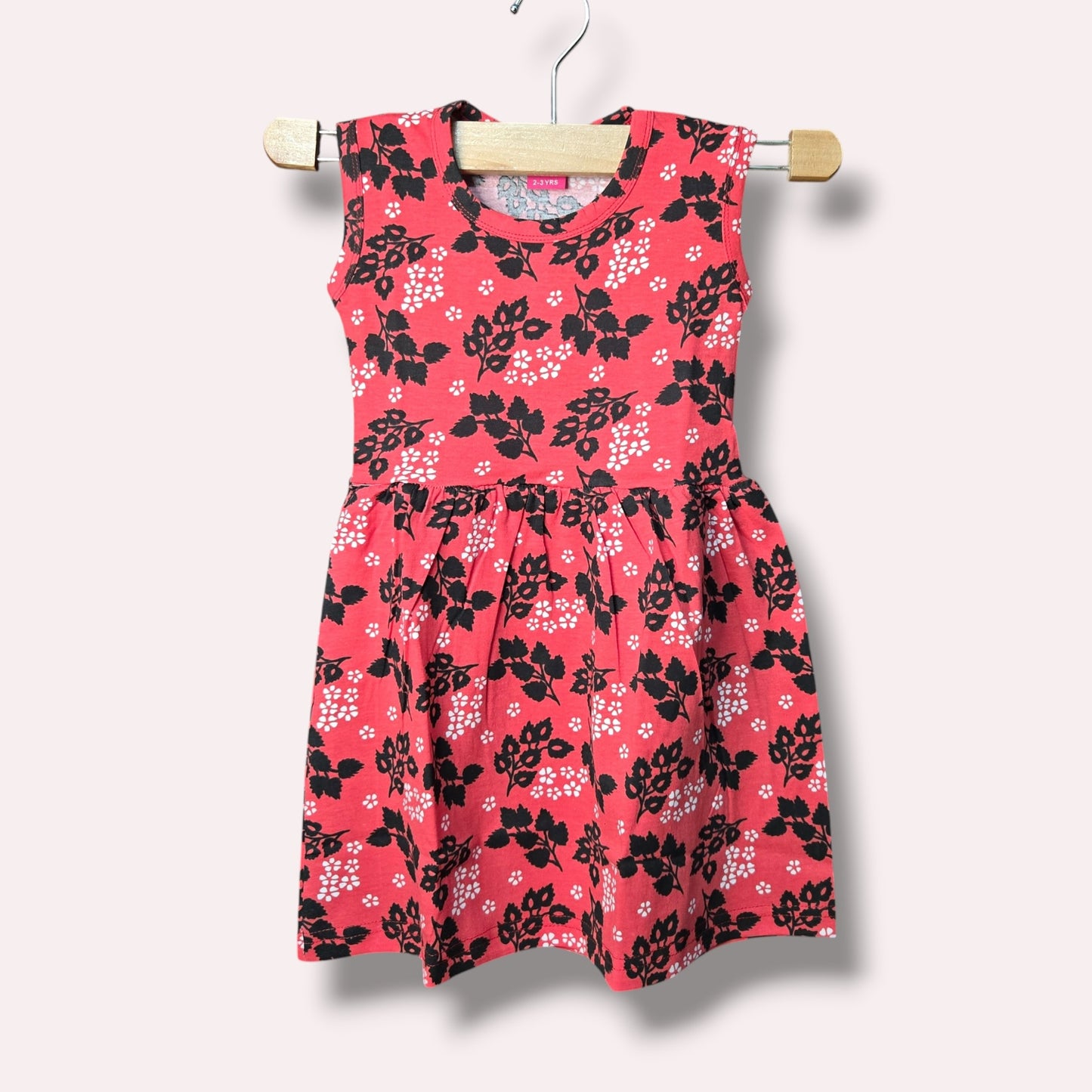 Coral pink baby sleeveless frock with black and white floral printed design