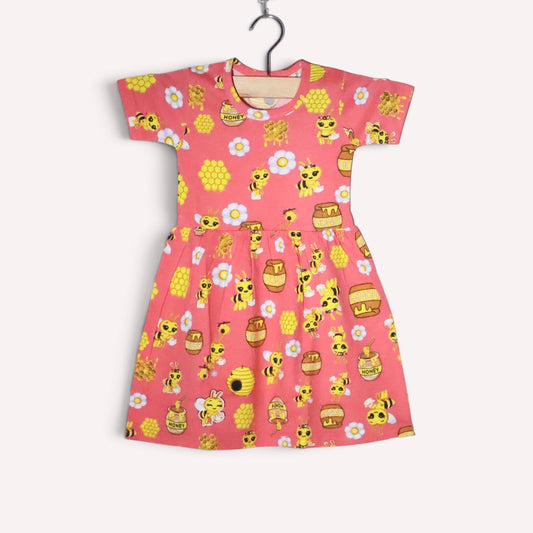 Bright peach baby frock with an allover bee, honeycomb and honey jar print, accented with white flowers, featuring short sleeves and a gathered waist