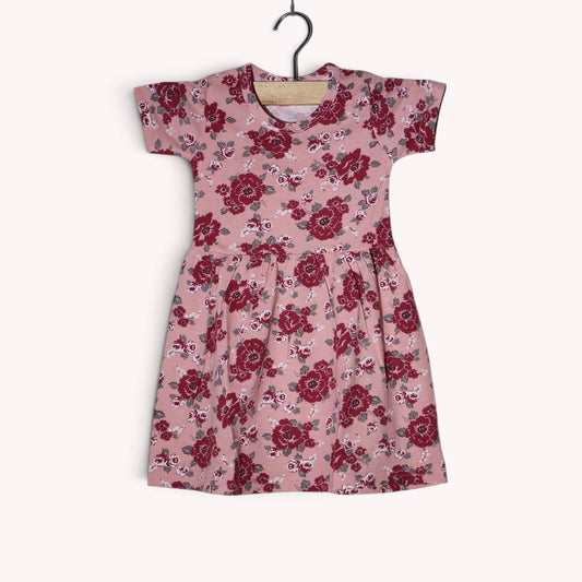 Dusty pink baby frock with an allover floral print in burgundy, maroon, white and grey, featuring short sleeves and a gathered waist
