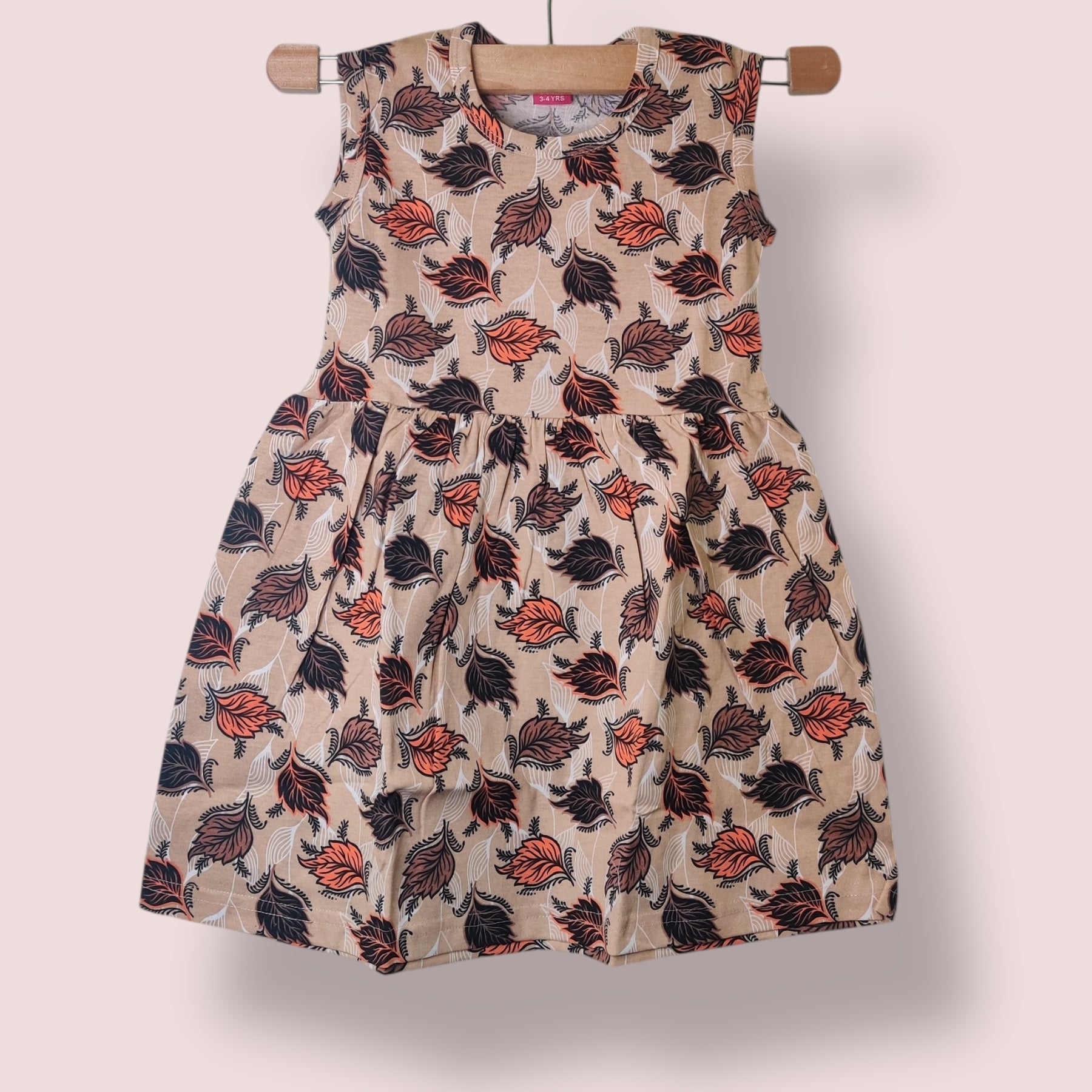 Sandy beige toddler sleeveless frock with all-over leaf print